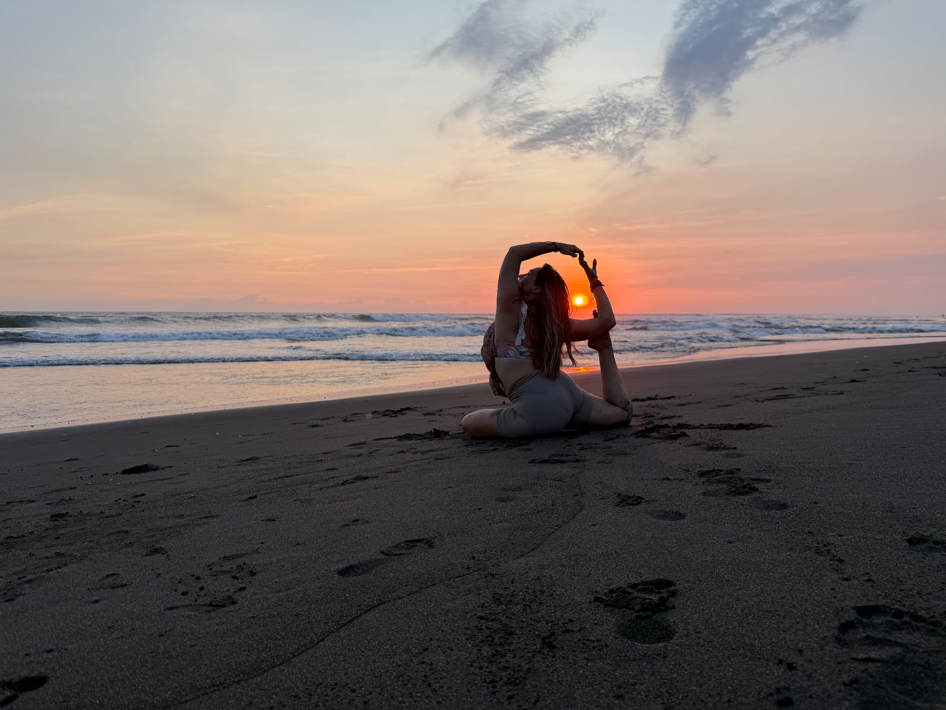 Michelle in een yogahouding op het strand bij zonsondergang